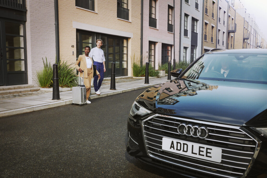 man and woman walking from colourful houses to Addison Lee executive car, airport Assured service