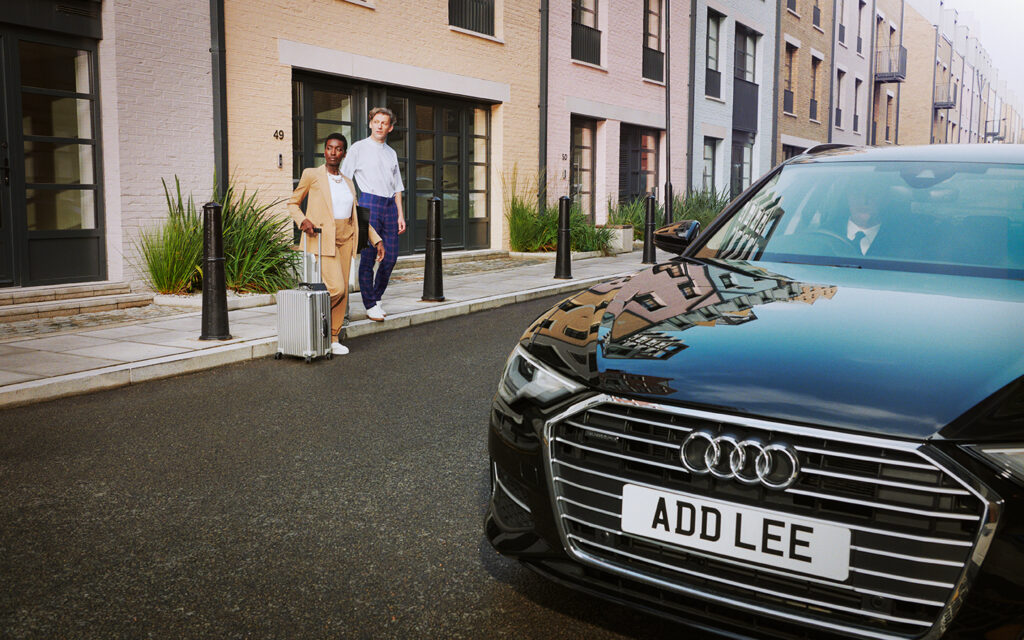 Addison Lee executive car with man and woman getting in with suitcase