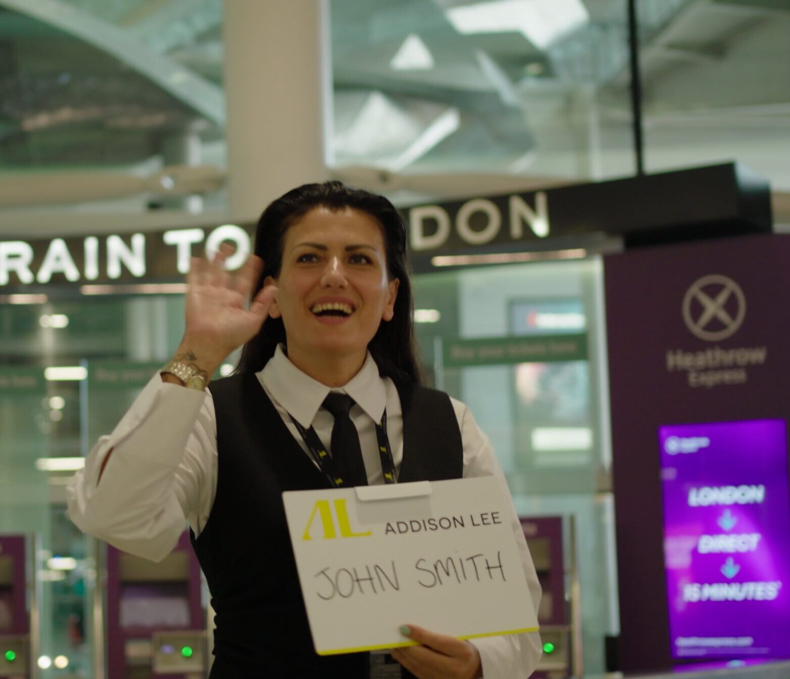 Addison Lee driver greeting a passenger at the airport arrivals with a name board