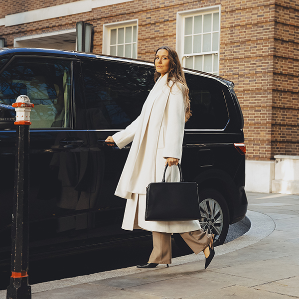 Woman walking into an Addison Lee taxi to go to the airport