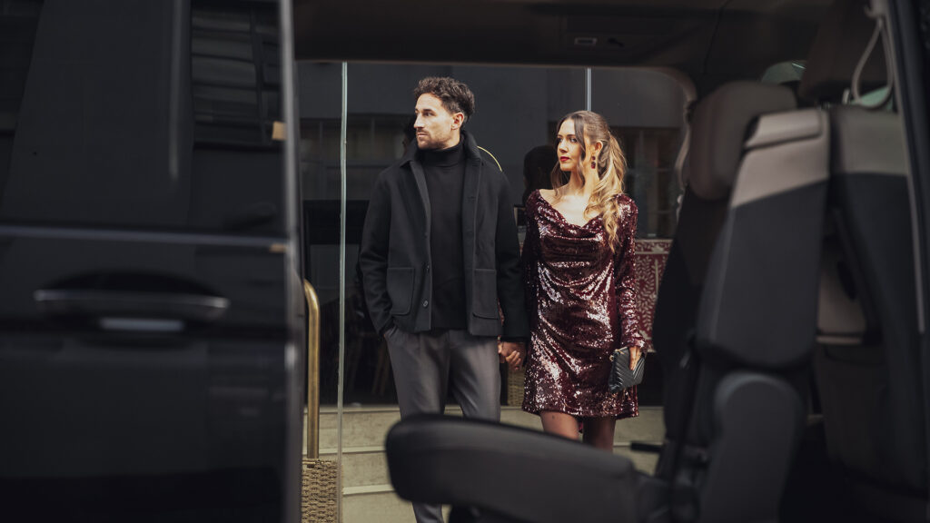 A couple holding hands and about to get into an Addison Lee taxi in London