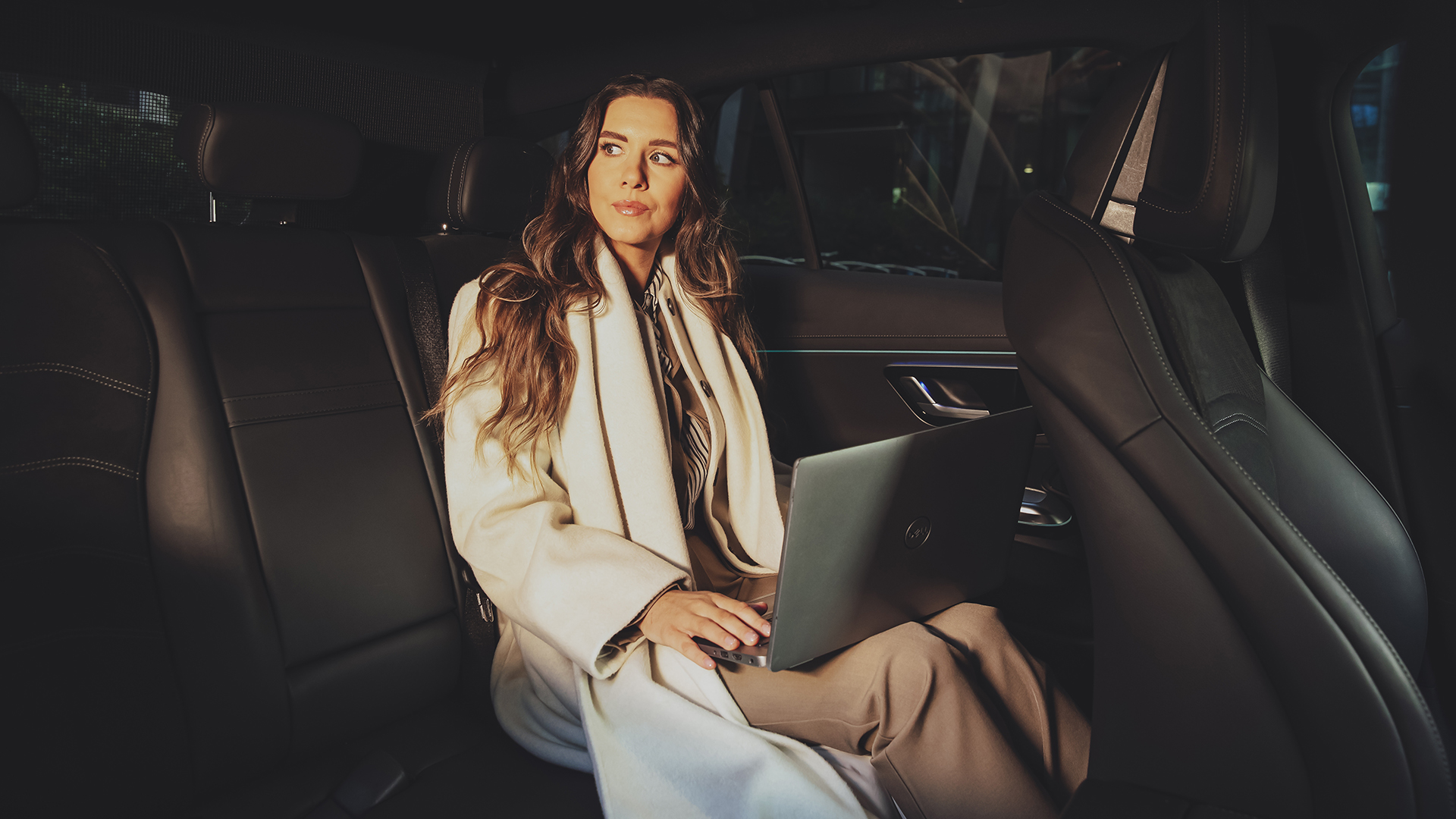 Woman in an Addison Lee taxi working on a laptop