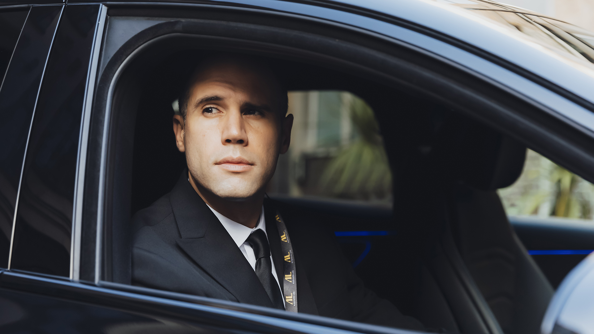 Addison Lee chauffeur driving a taxi and dressed in a suit