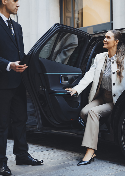 Addison Lee chauffeur opening a car door for a woman