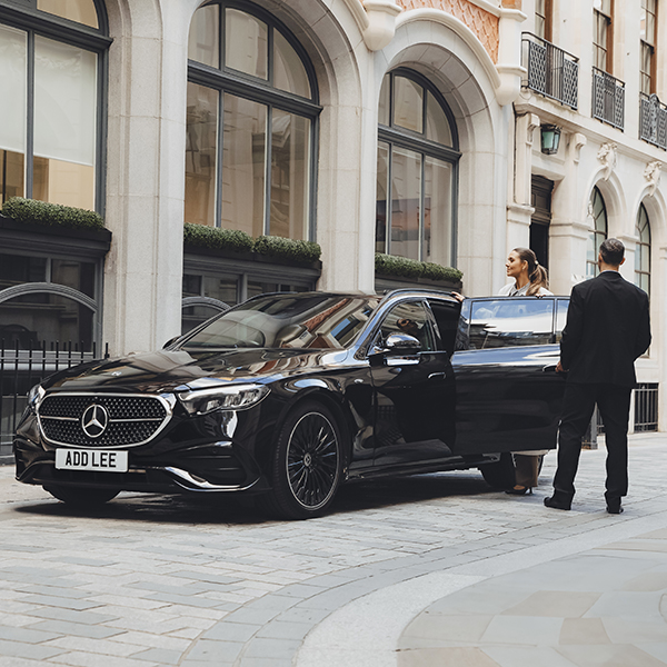 Addison Lee chauffeur opening car door of an executive vehicle for a woman