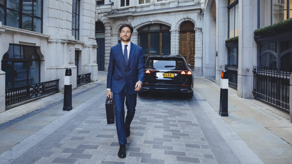 Businessman walking out of an Addison Lee executive taxi holding a briefcase