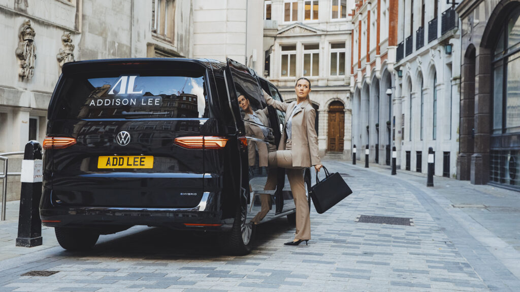 Businesswoman walking into an Addison Lee taxi wearing a suit