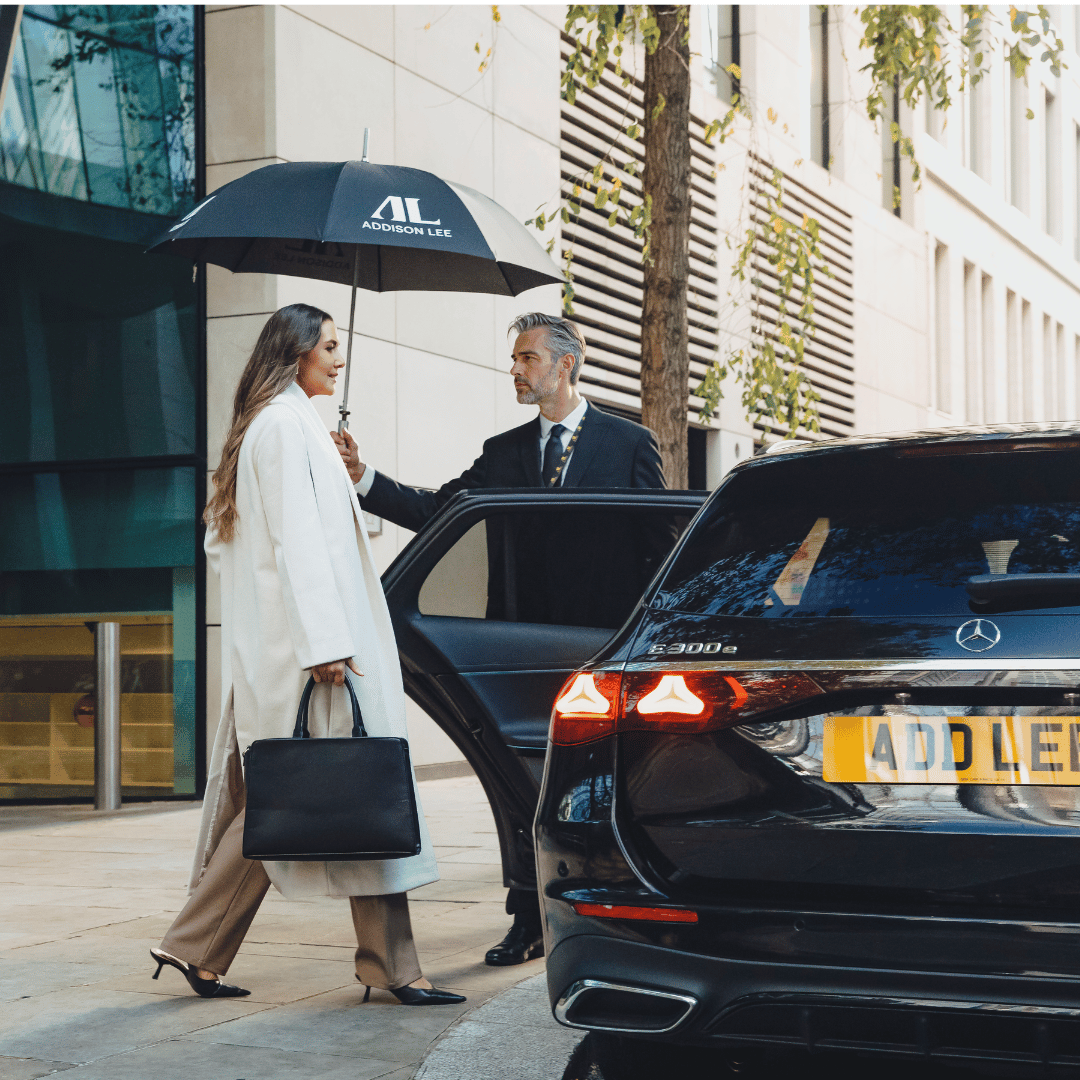 Driver holding Umbrella for businesswoman