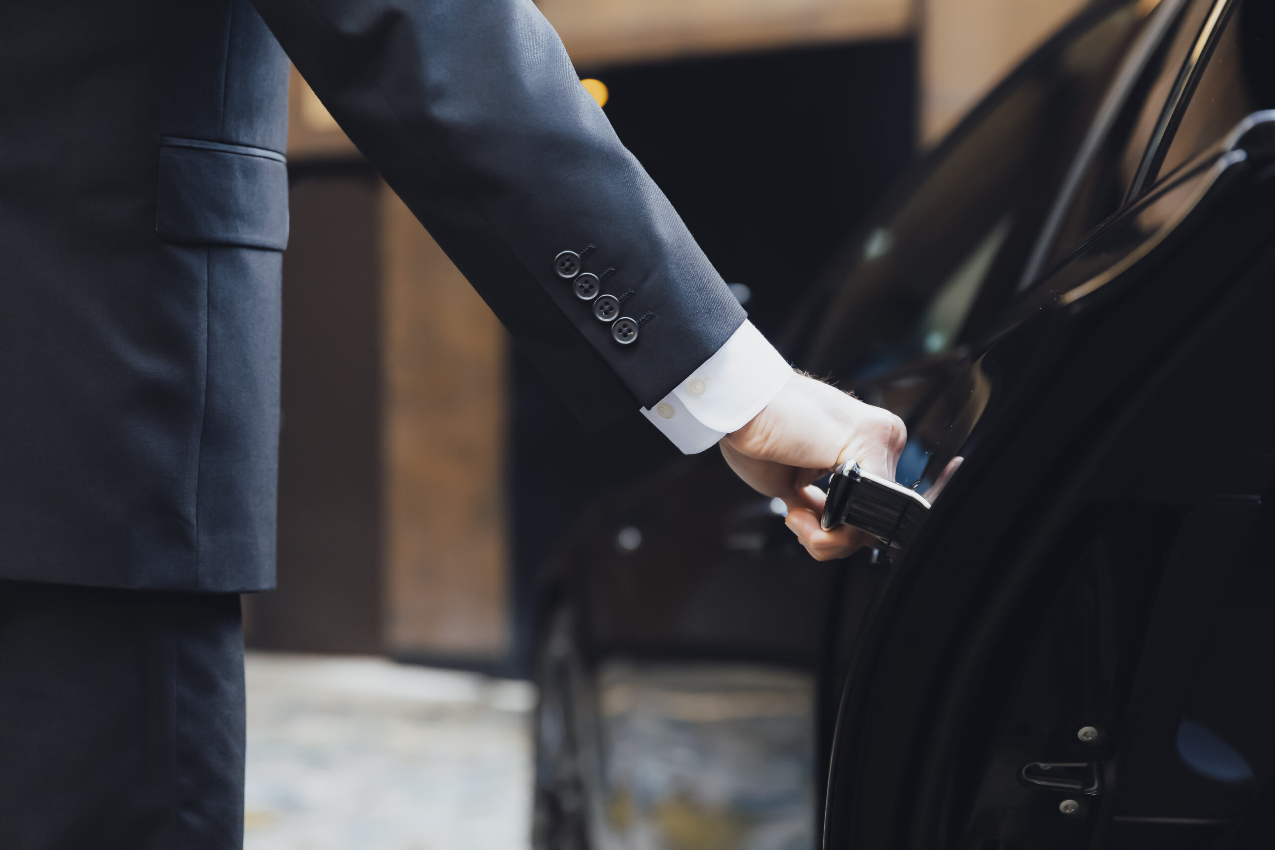 Chauffeur opening the door of an executive Addison Lee taxi