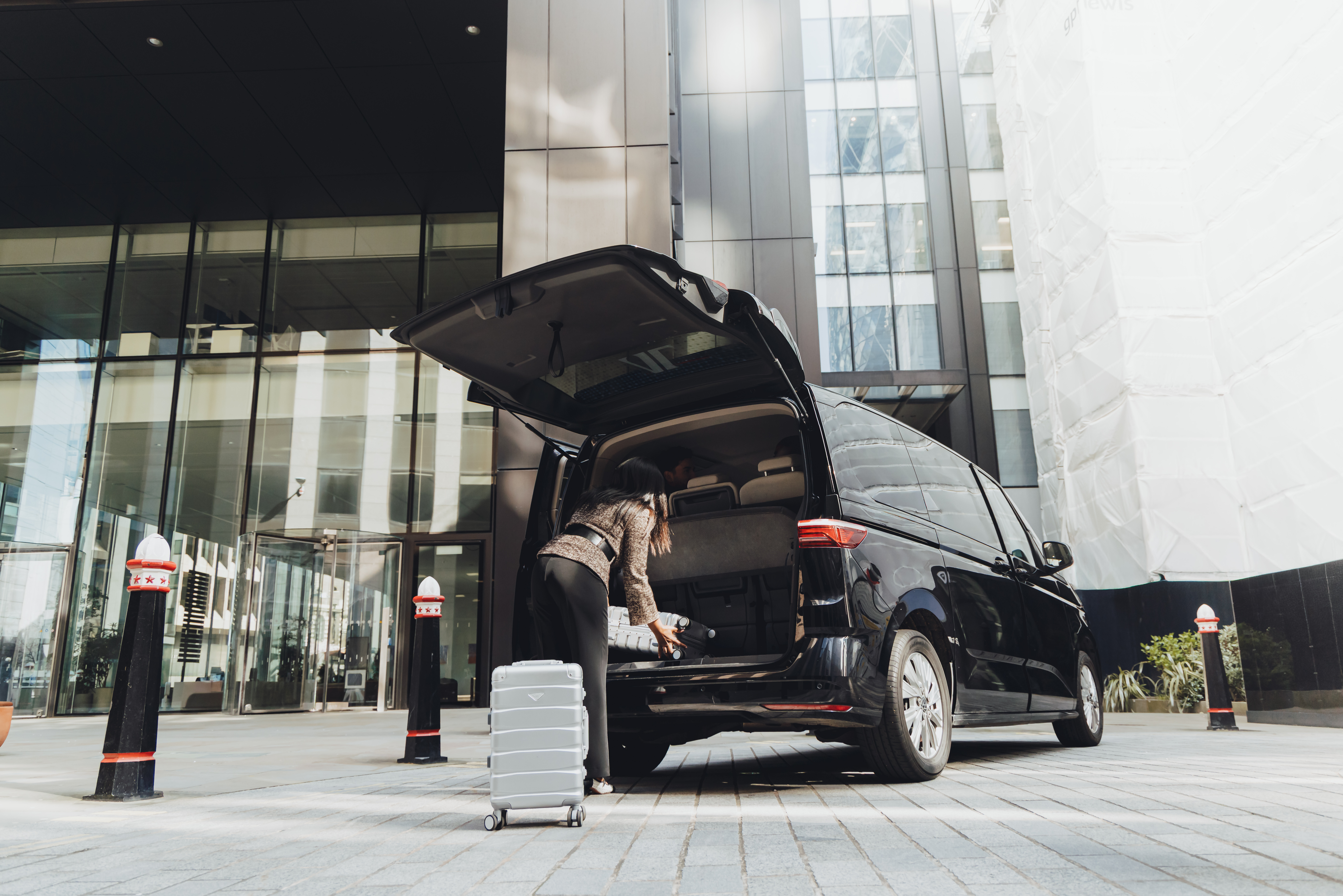 Addison Lee driver putting luggage into the boot of a car for an airport transfer