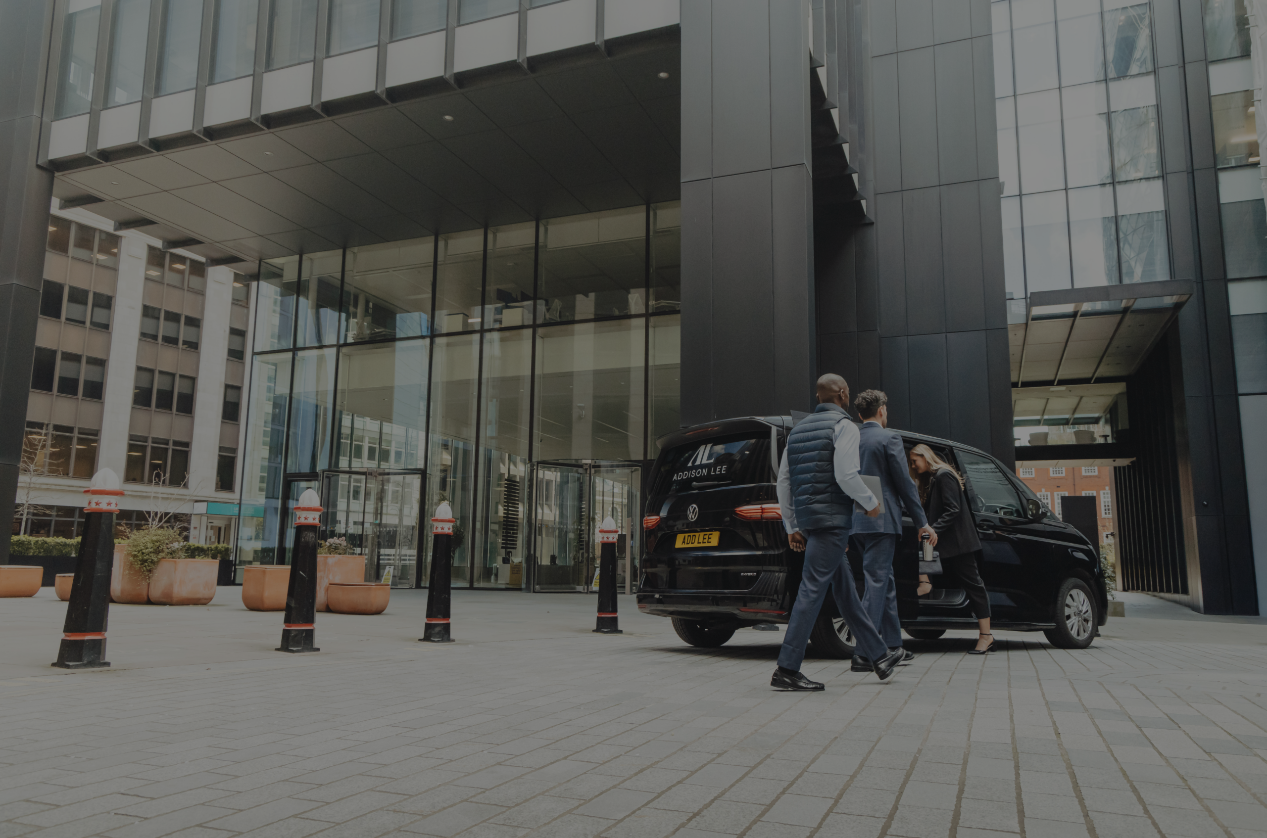 3 corporate workers going into a multivan outside of an office in the city of London